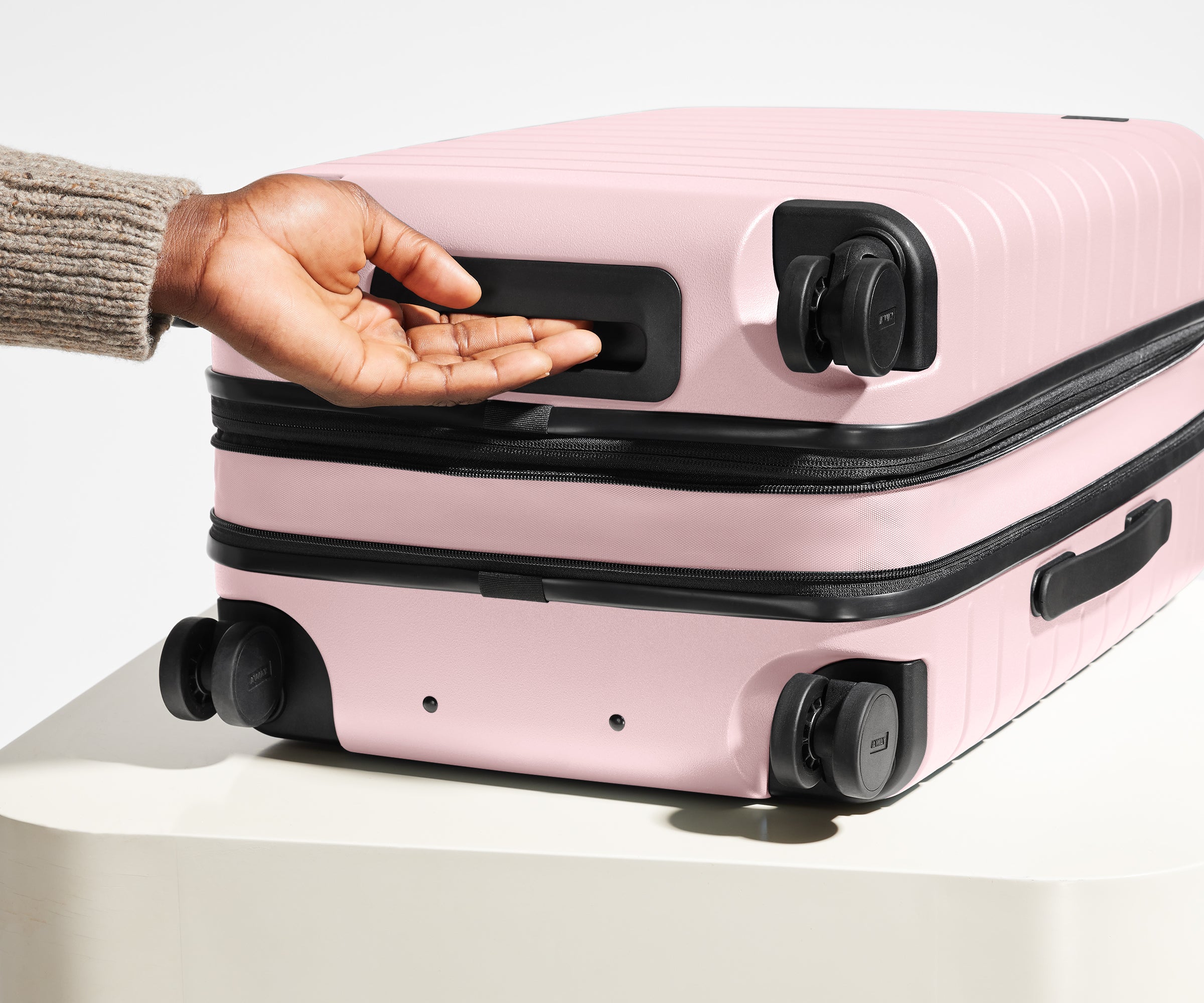 The Carry-On Flex suitcase in Blush Pink shown from below highlighting the underside grab handle