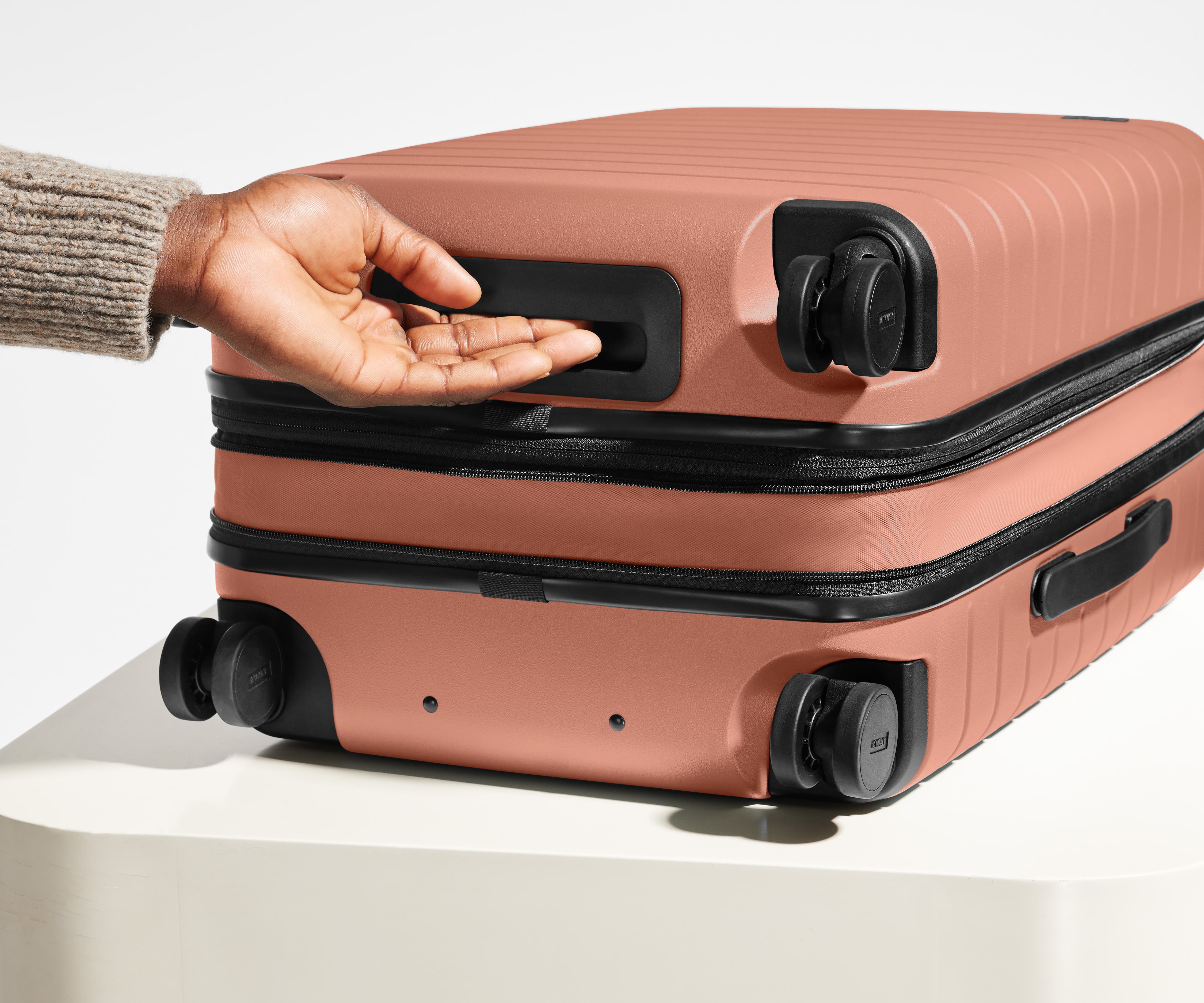 The Carry-On Flex suitcase in Clay Pink shown from below highlighting the underside grab handle