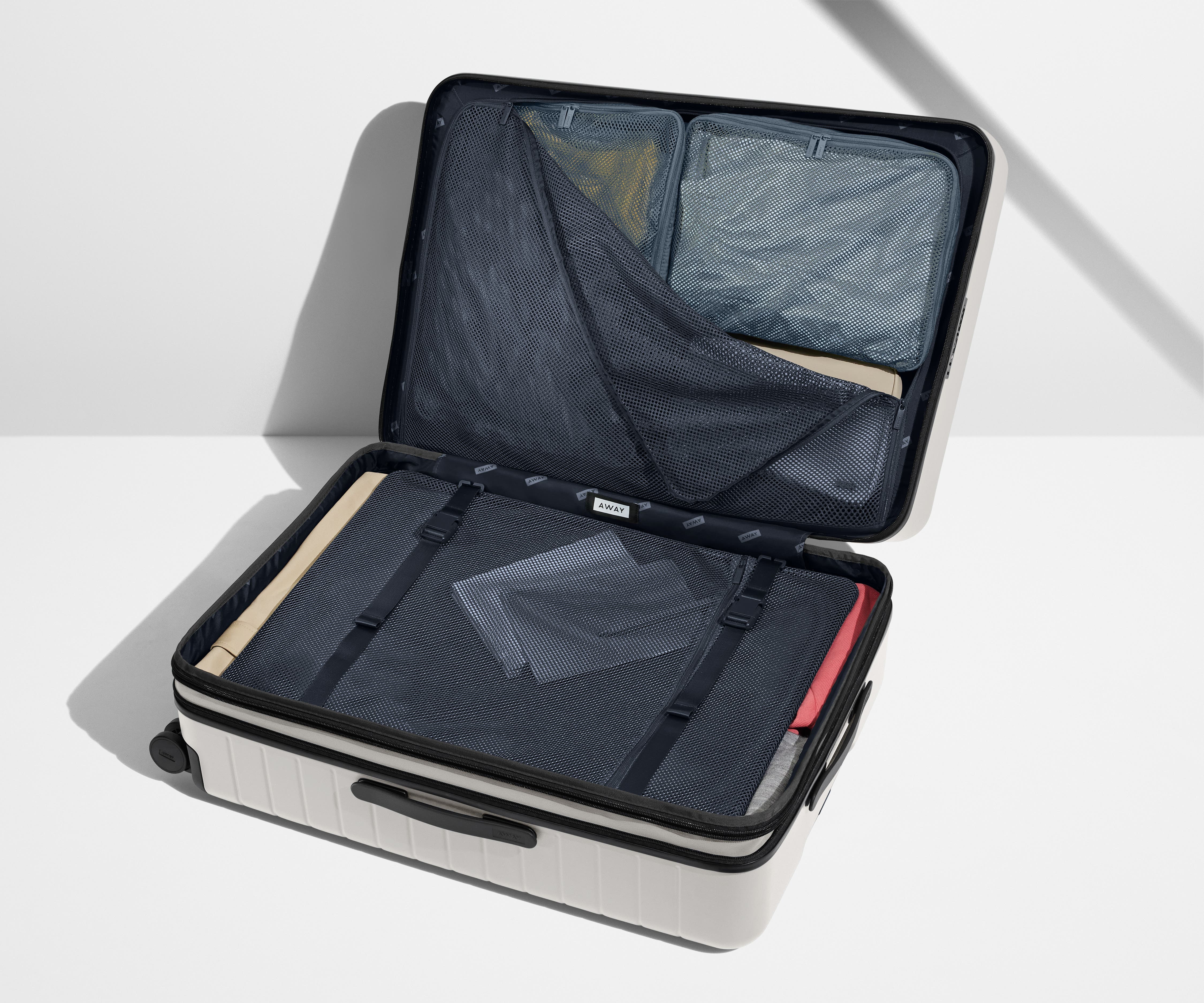The Large Flex suitcase shown open on its side and packed with Away's packing organizers to show capacity and the interior compression system, designed to help you pack more in