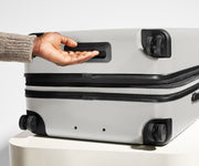 The Large Flex suitcase in Cloud Gray shown from below highlighting the underside grab handle