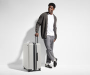 6'1" person walking with The Large Flex suitcase