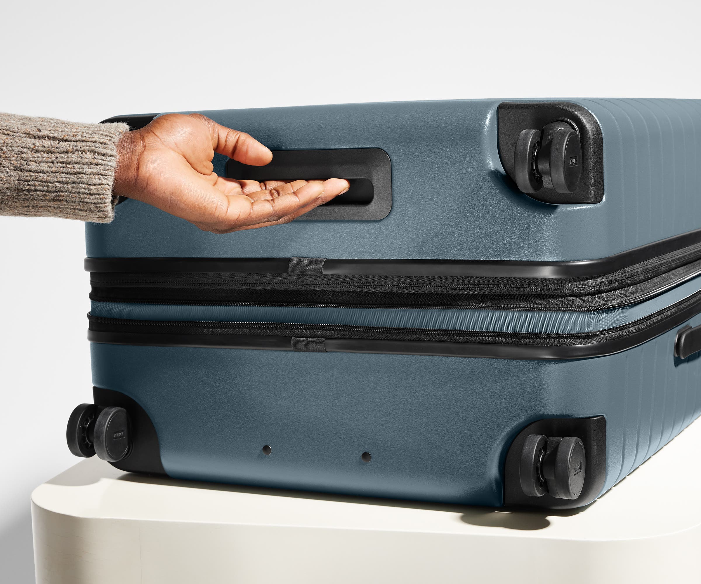 The Medium Flex suitcase in Coast Blue shown from below highlighting the underside grab handle