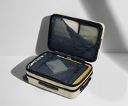 The Carry-On Flex suitcase in Salt White (Gloss) shown open on its side and packed with Away's packing organizers to show capacity and the interior compression system, designed to help you pack more in