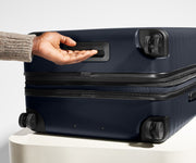 The Medium Flex suitcase in Navy Blue shown from below highlighting the underside grab handle