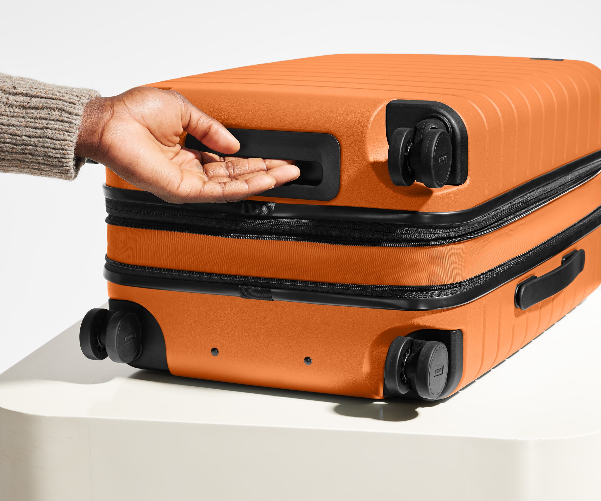 The Carry-On Flex suitcase in Sorbet Orange shown from below highlighting the underside grab handle