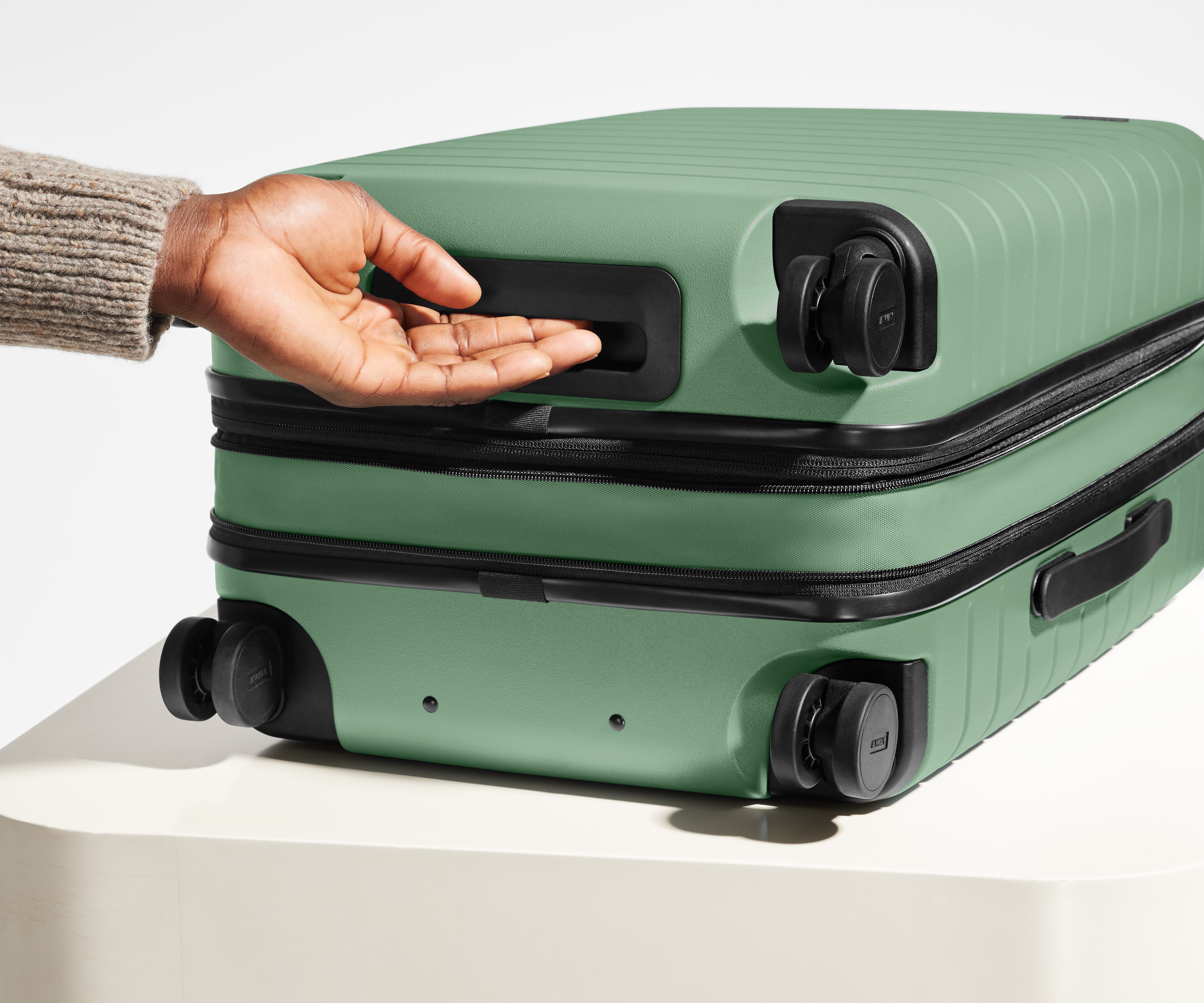 The Carry-On Flex suitcase in Sea Green shown from below highlighting the underside grab handle