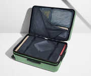 The Large Flex suitcase in Sea Green shown open on its side and packed with Away's packing organizers to show capacity and the interior compression system, designed to help you pack more in