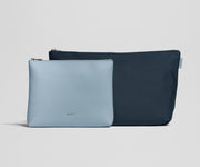 Two pouches, one light blue and one navy, on a light gray background