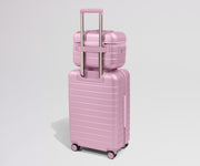 Pink suitcase with a smaller pink suitcase on top against a light gray background