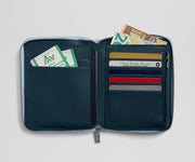 Open navy blue wallet with various cards and money on a light gray background