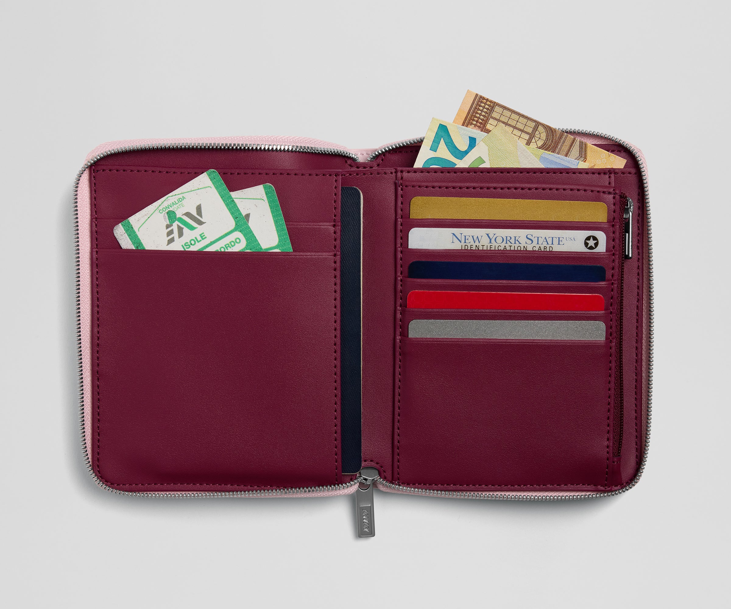 Open maroon wallet with various cards and money on a light gray background
