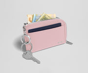 Pink wallet with keys and money on a light gray background