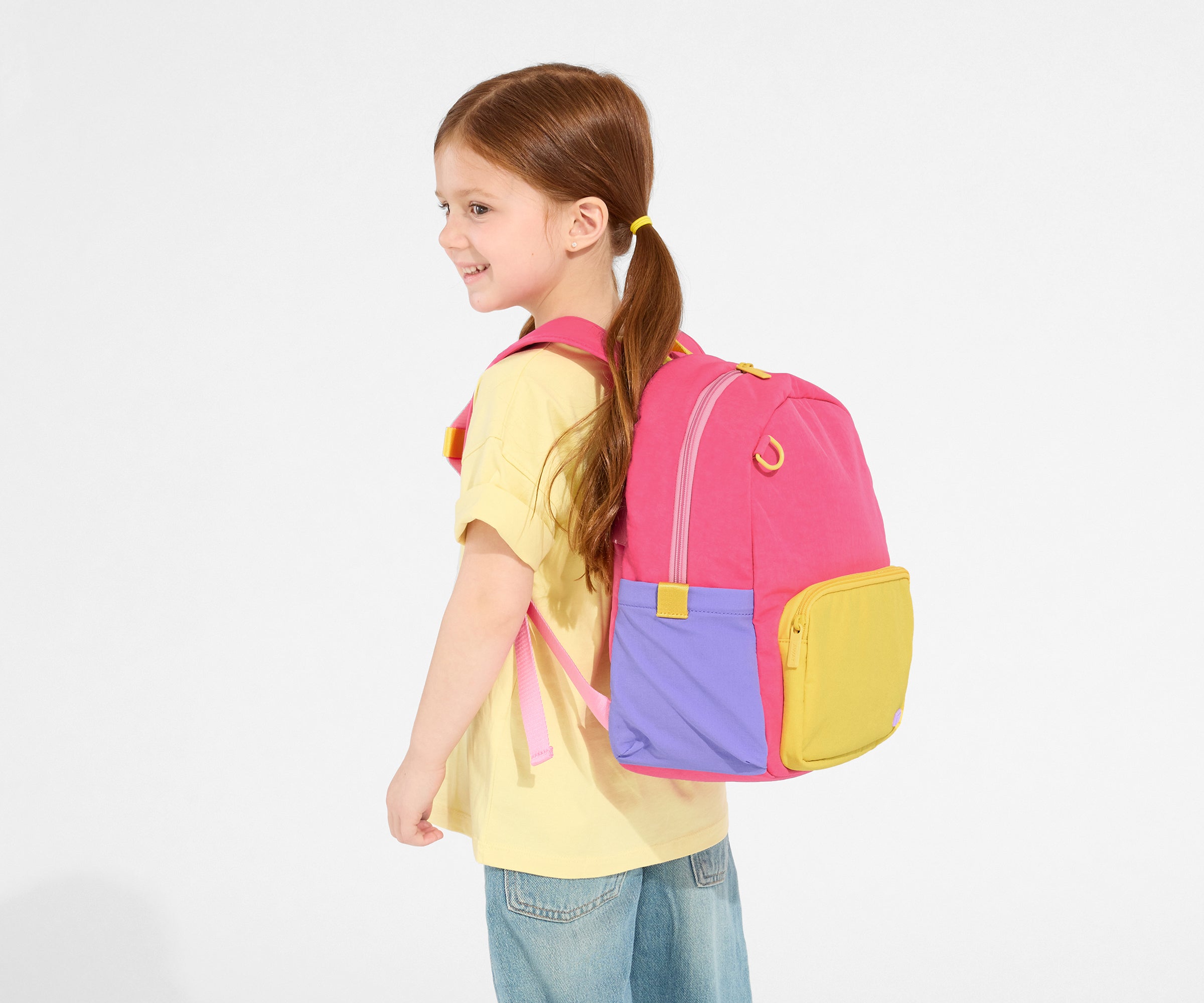 A child model wearing the Kids Backpack in Cotton Candy Pink with the chest strap in use