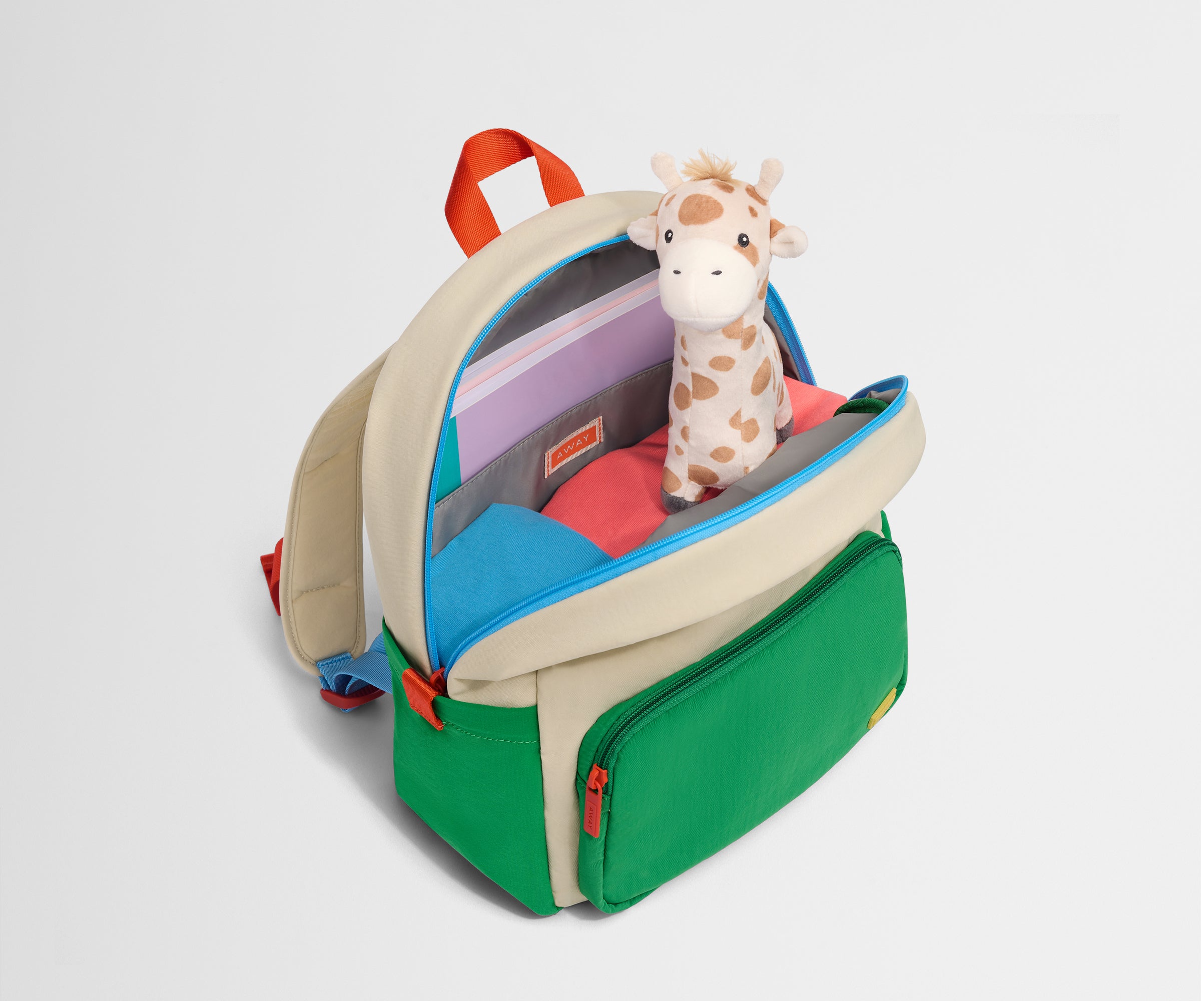 Top down product view of the packed Kids Backpack in Marshmallow White, showing how it fits clothes, tablet, notebook and headphones.