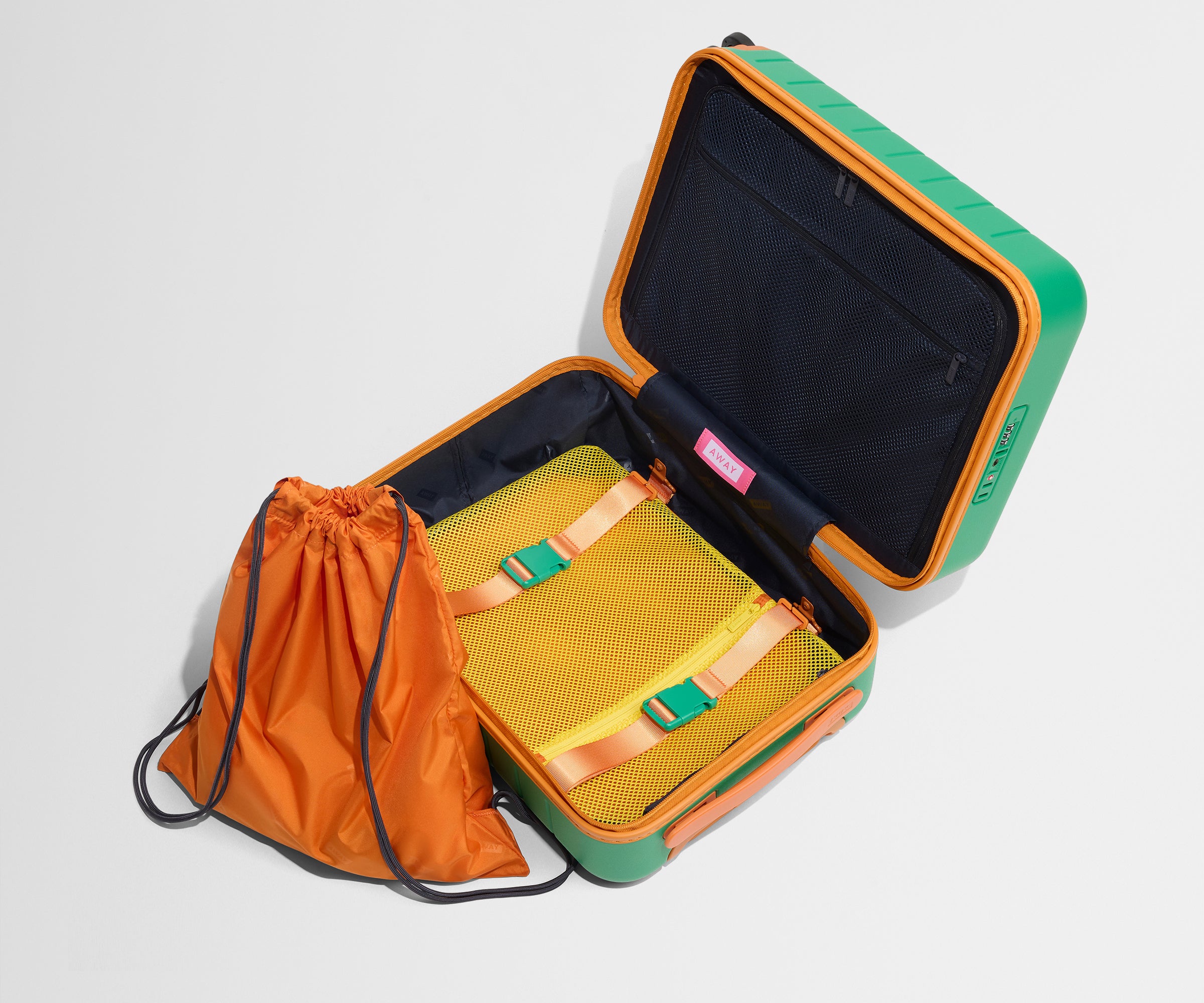 The Kids Carry-On suitcase in Froggy Green shown open and empty on its side to show capacity, and an orange laundry bag can double as a backpack for smaller travelers.