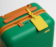 The Kids Carry-On suitcase in Froggy Green shown shown from above highlighting TSA-approved combination lock and colorful silicone luggage tag