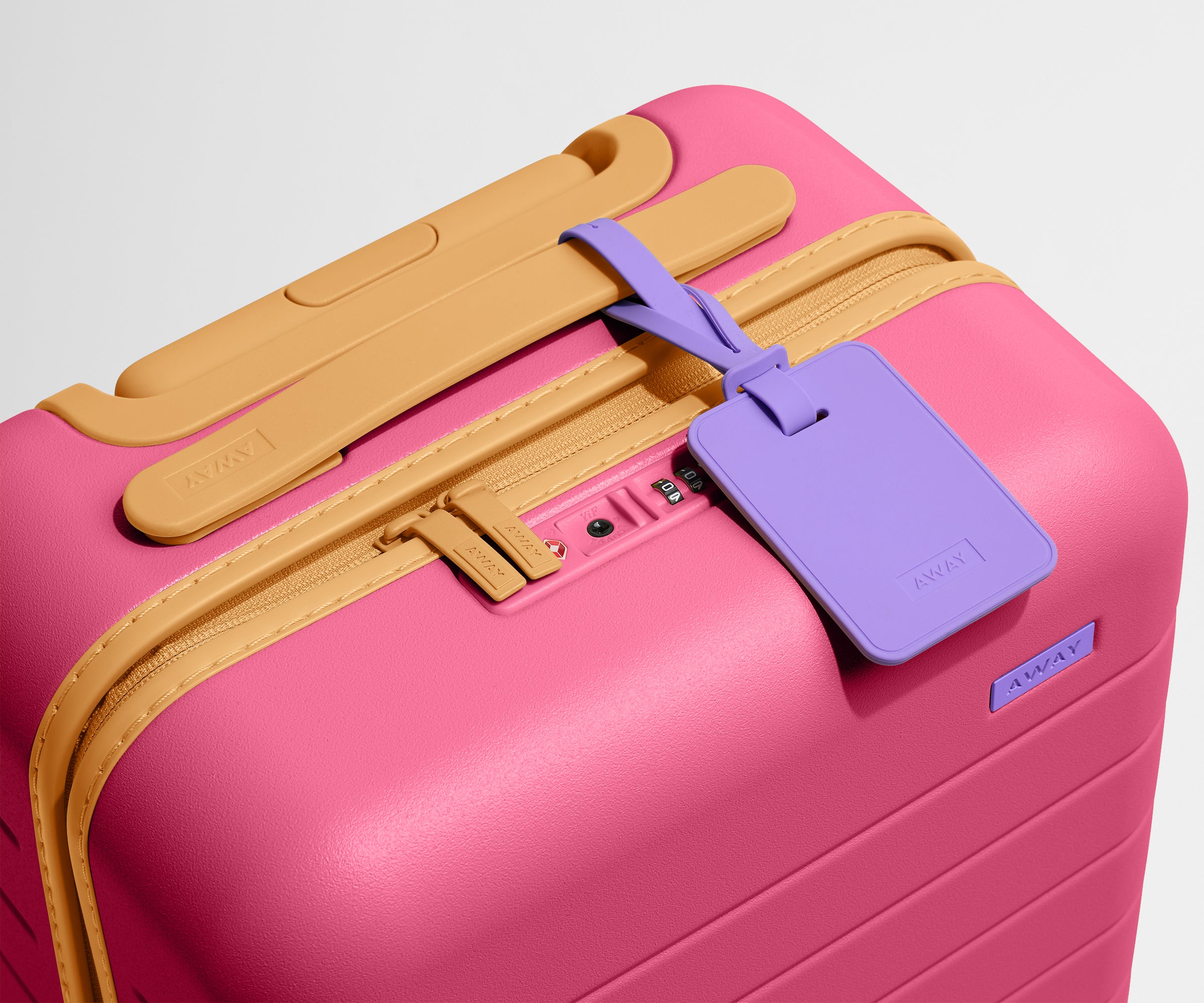 The Kids Carry-On suitcase in Cotton Candy Pink shown shown from above highlighting TSA-approved combination lock and colorful silicone luggage tag