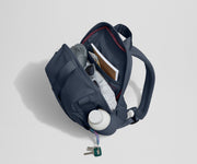 Daypack packed with a light jacket, sunglasses, notebook, map, and other travel gear. Water bottle featured in the exterior water bottle pocket.