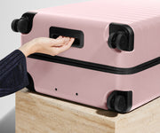 The Large suitcase in Blush Pink shown from below highlighting the underside grab handle