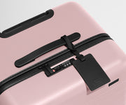 The Trunk suitcase in Blush Pink shown shown from above highlighting TSA-approved combination lock and recycled leather luggage tag