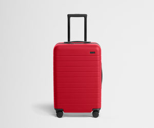 Red suitcase with black wheels on a light gray background