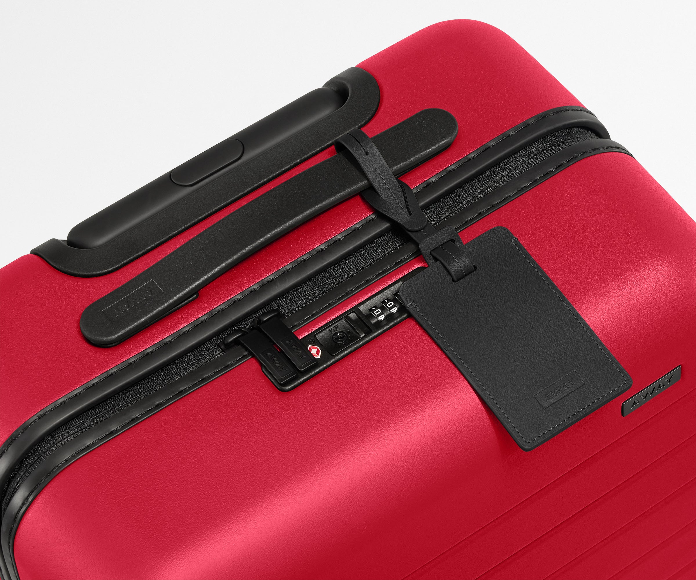 Red suitcase with black handle and tag on a white background