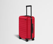 Red suitcase with black handle and wheels on a light gray background