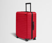 Red suitcase with black handle and wheels on a light gray background