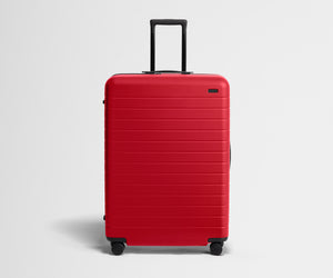Red suitcase with black handle on a light gray background