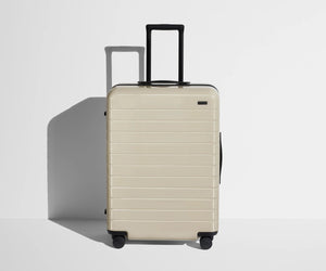 Front product view of The Medium suitcase in Salt White (Gloss) with raised handle