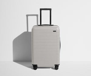 Front product view of The Bigger Carry-On suitcase in Cloud Gray with raised handle