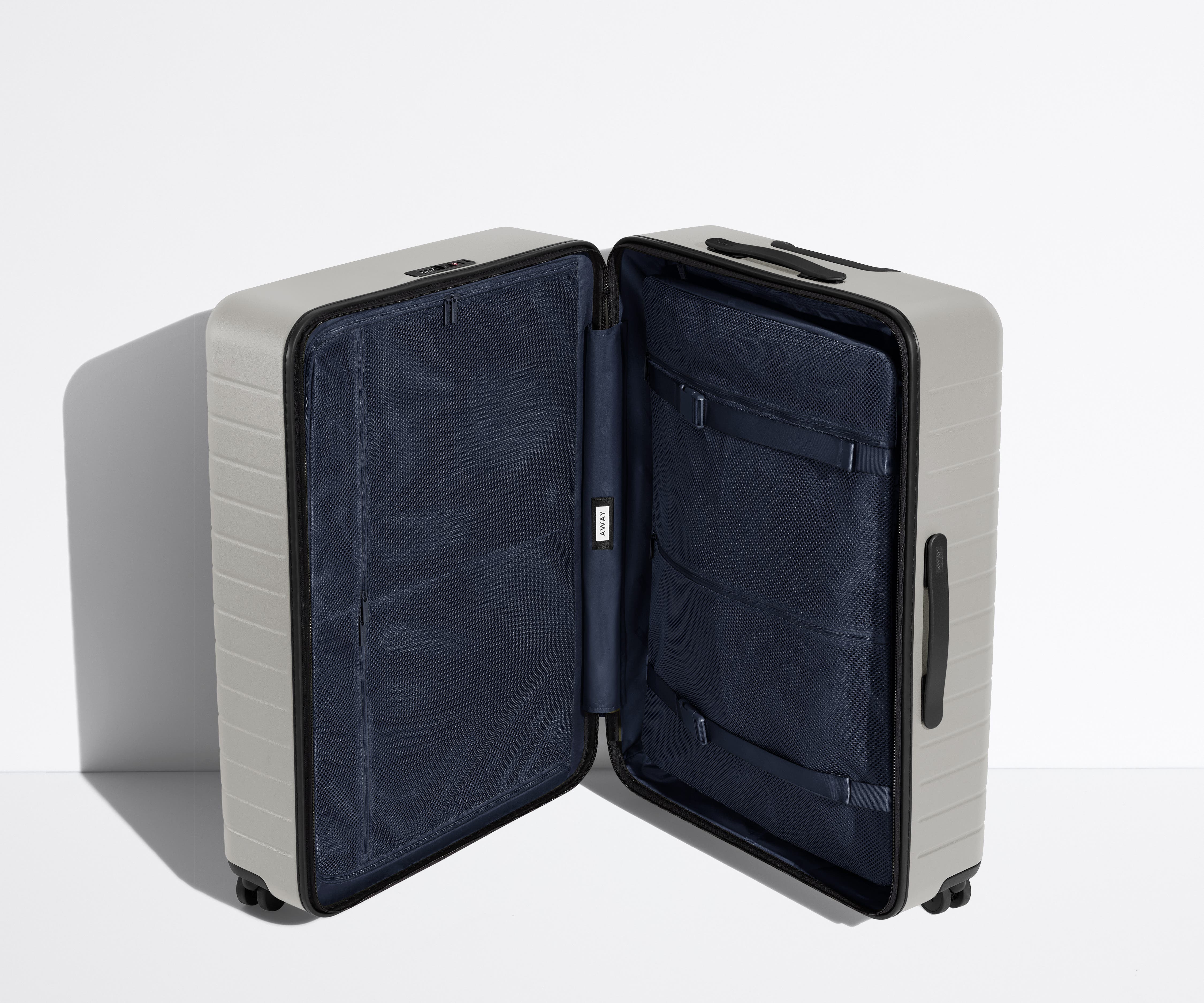 The Large suitcase in Cloud Gray shown open in an upright position to show interior organization and compression system