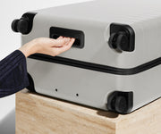The Large suitcase in Cloud Gray shown from below highlighting the underside grab handle