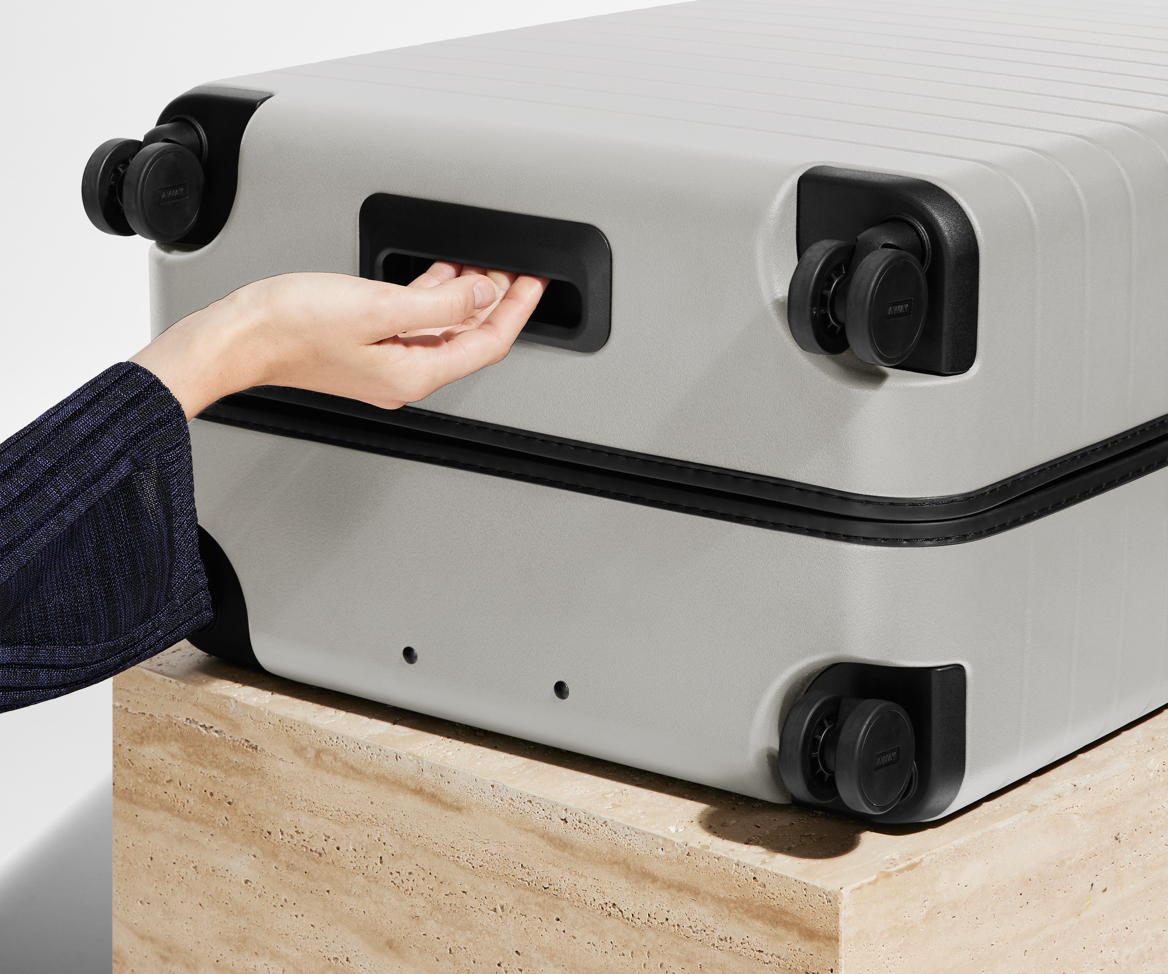 The Medium suitcase in Cloud Gray shown from below highlighting the underside grab handle