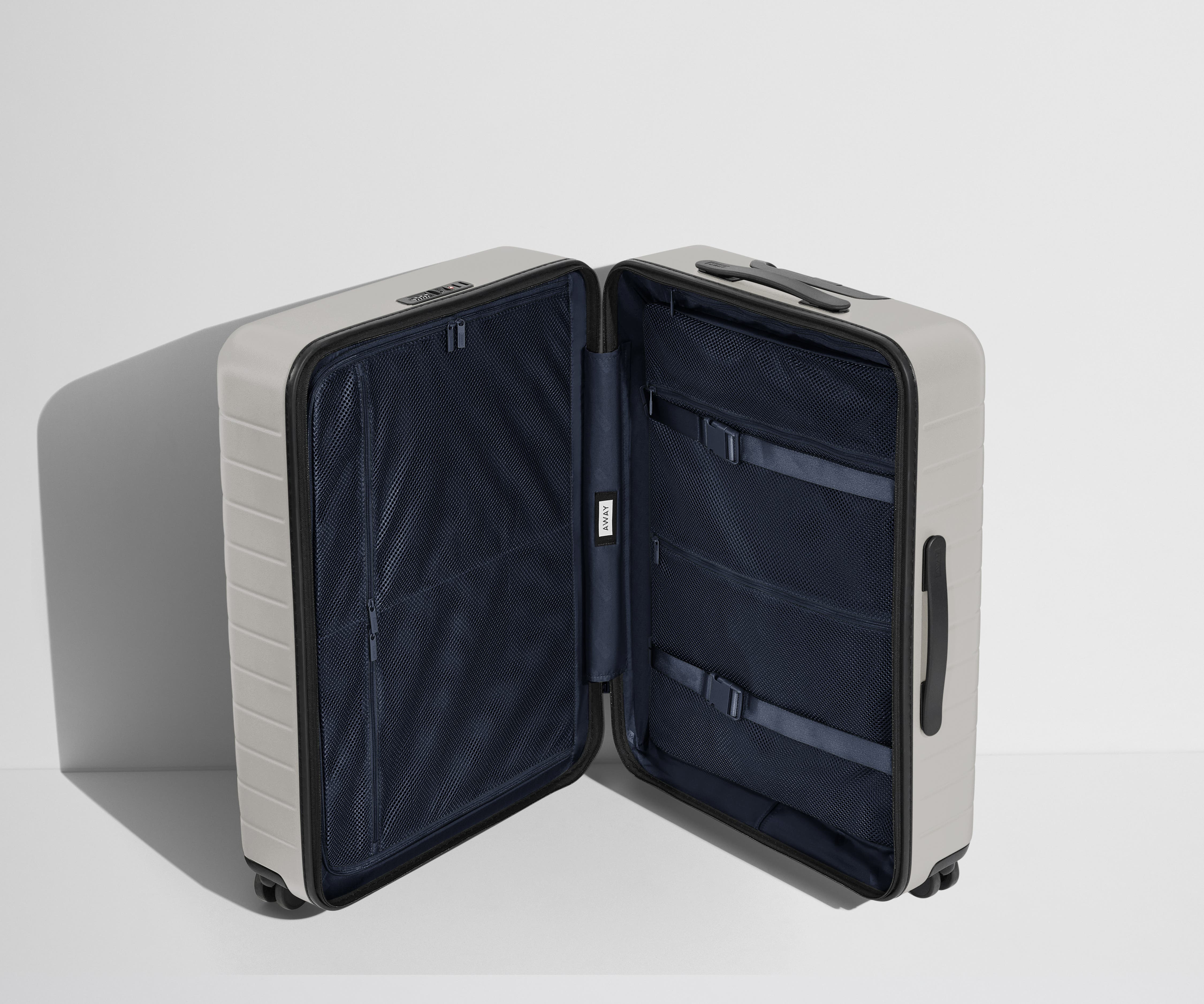 The Medium suitcase in Cloud Gray shown open in an upright position to show interior organization and compression system