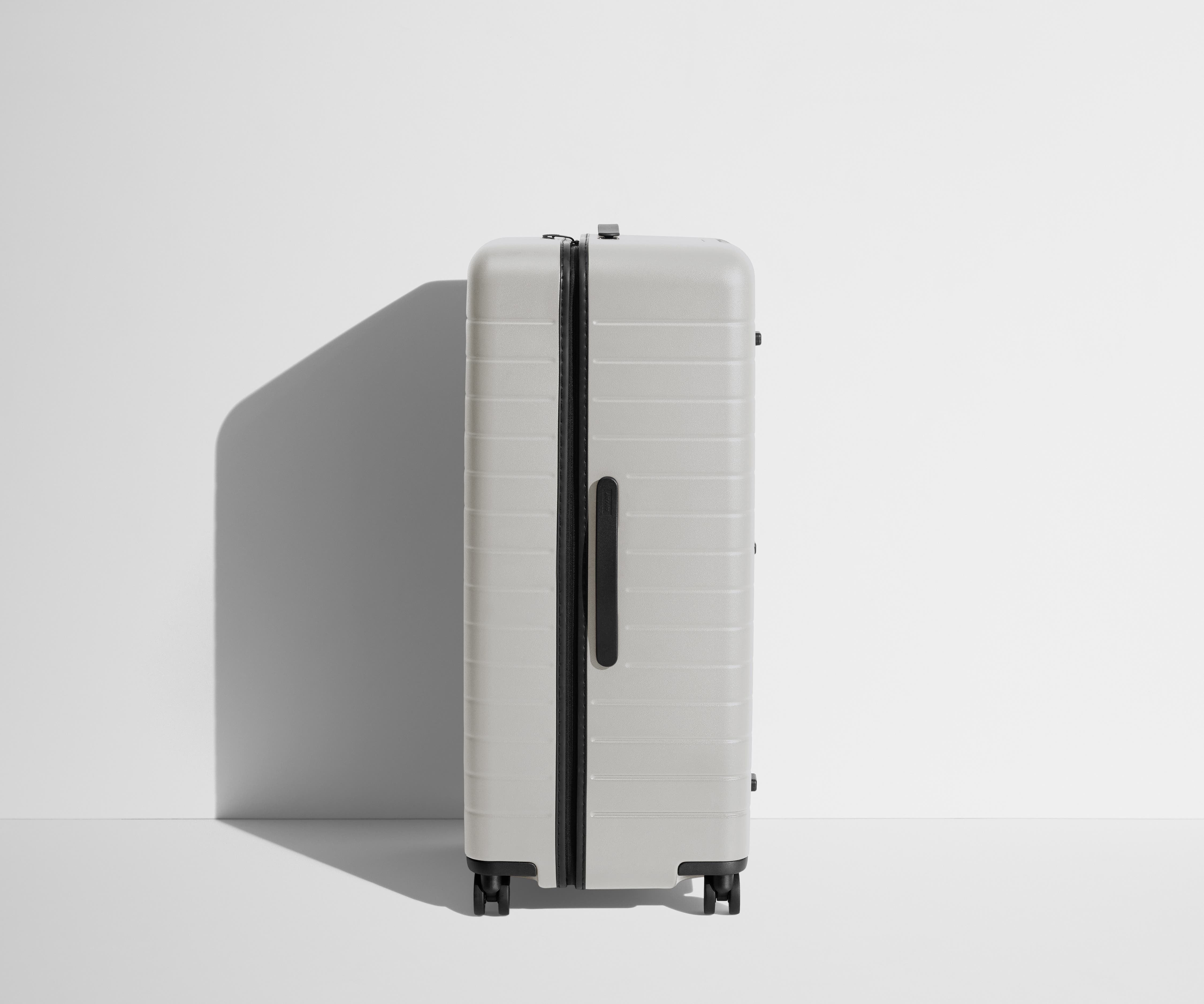 Side product view of The Trunk suitcase in Cloud Gray to show the slimmer top lid and deeper main compartment for easy access and packing