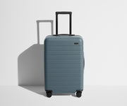 Front product view of The Bigger Carry-On suitcase in Coast Blue with raised handle