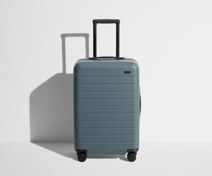 Front product view of The Bigger Carry-On suitcase in Coast Blue with raised handle