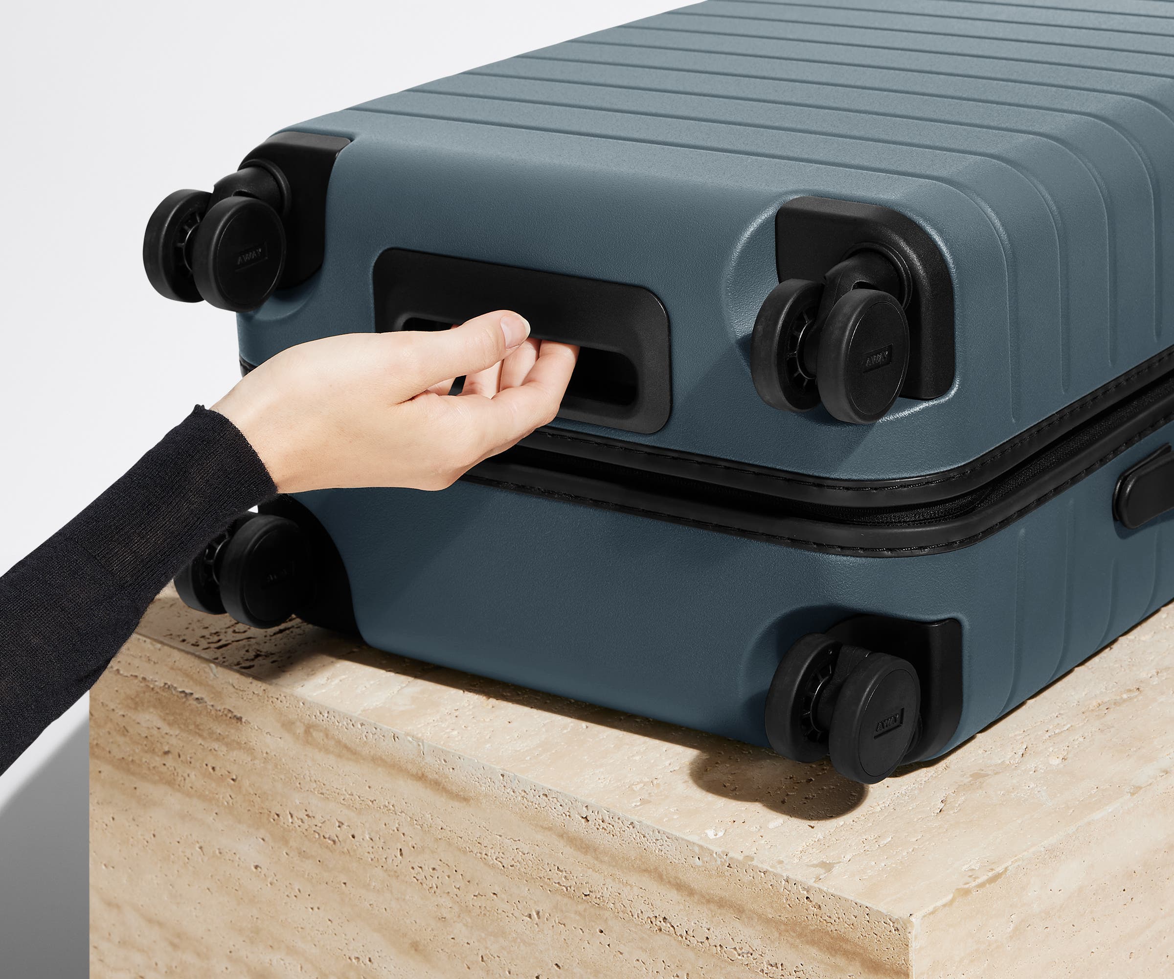 The Carry-On suitcase in Coast Blue shown from below highlighting the underside grab handle