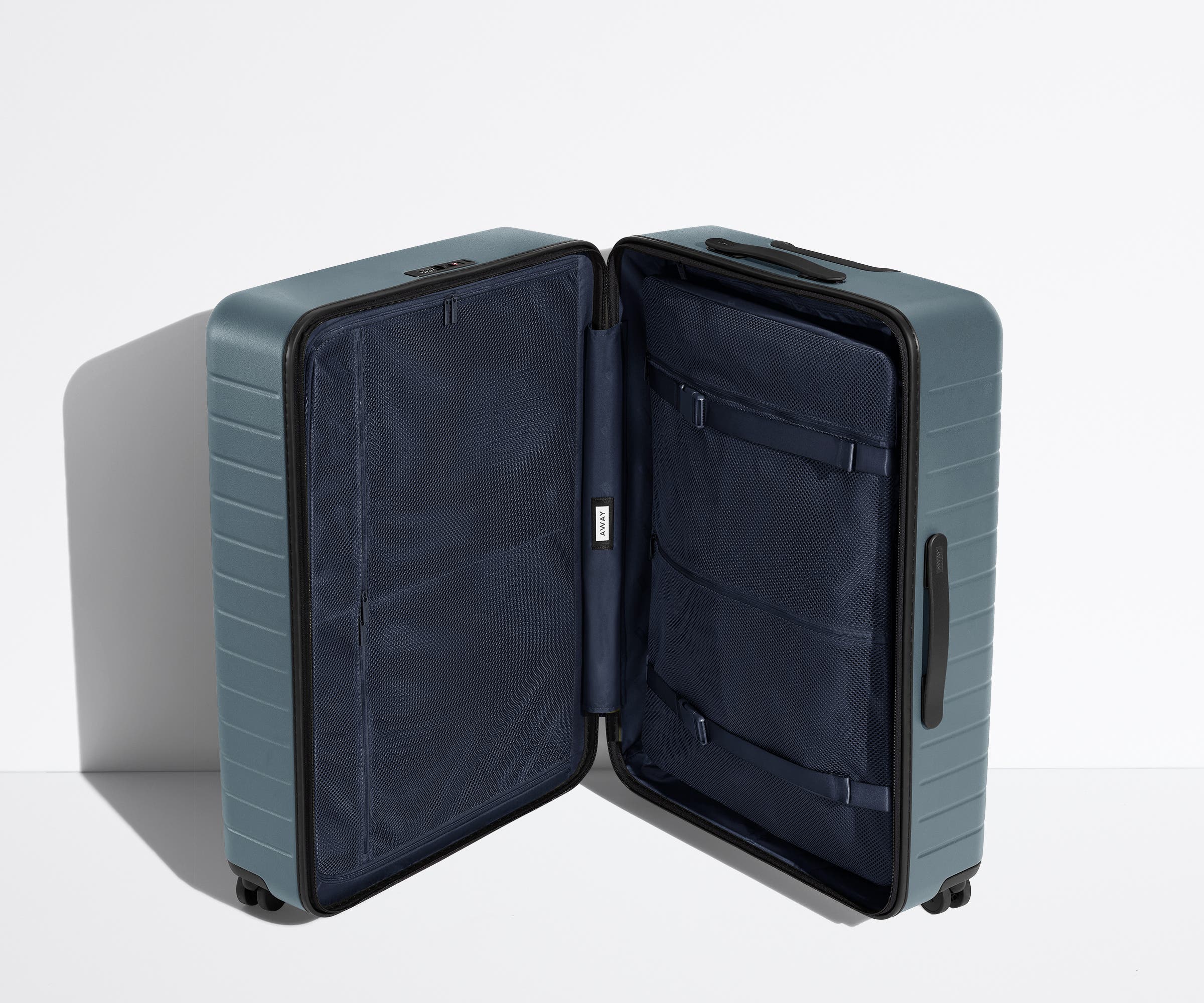 The Large suitcase in Coast Blue shown open in an upright position to show interior organization and compression system