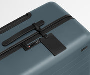 The Medium suitcase in Coast Blue shown shown from above highlighting TSA-approved combination lock and recycled leather luggage tag