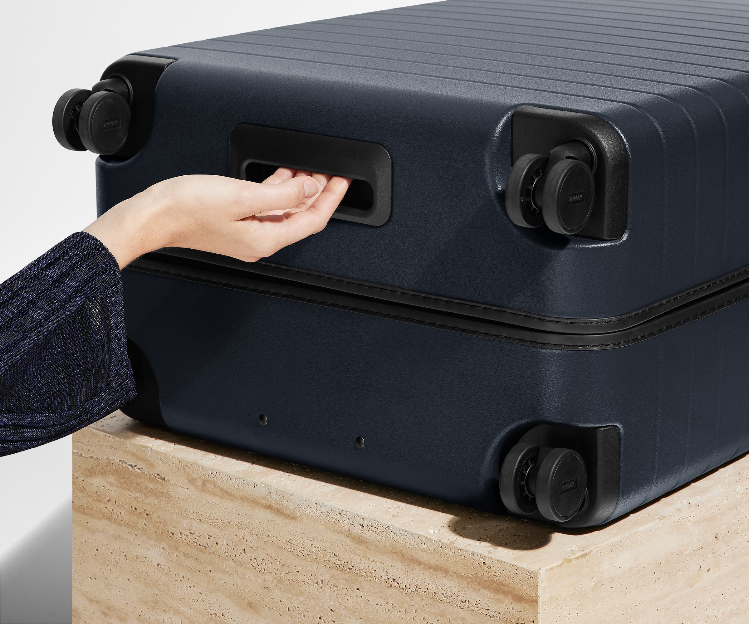 The Medium suitcase in Navy Blue shown from below highlighting the underside grab handle