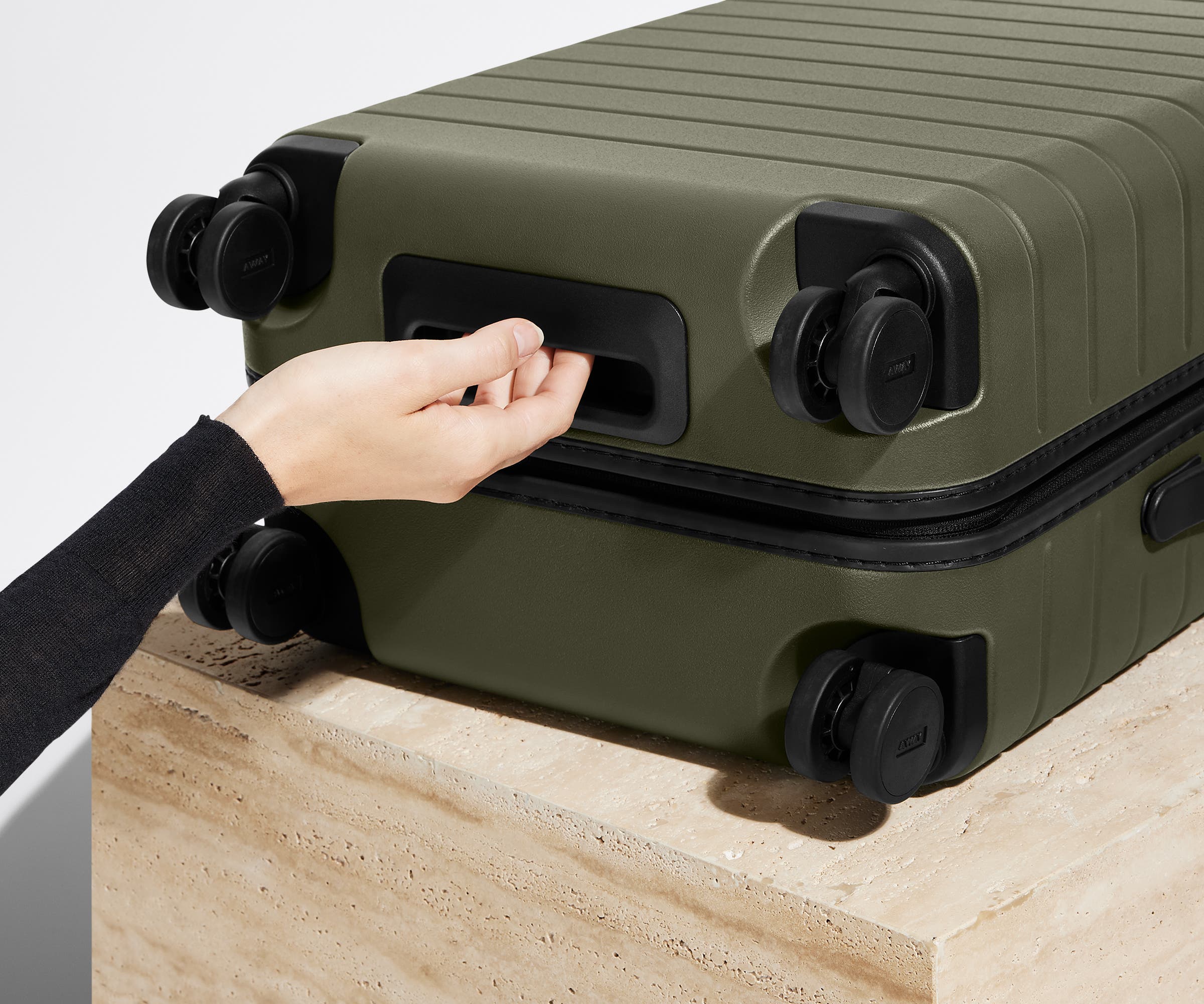 The Carry-On suitcase in Olive Green shown from below highlighting the underside grab handle