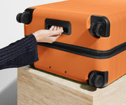 The Medium suitcase in Sorbet Orange shown from below highlighting the underside grab handle