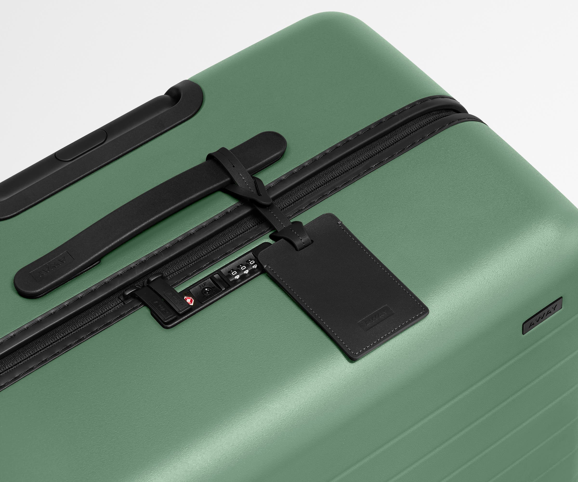 The Medium suitcase in Sea Green shown shown from above highlighting TSA-approved combination lock and recycled leather luggage tag