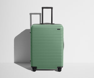 Front product view of The Medium suitcase in Sea Green with raised handle