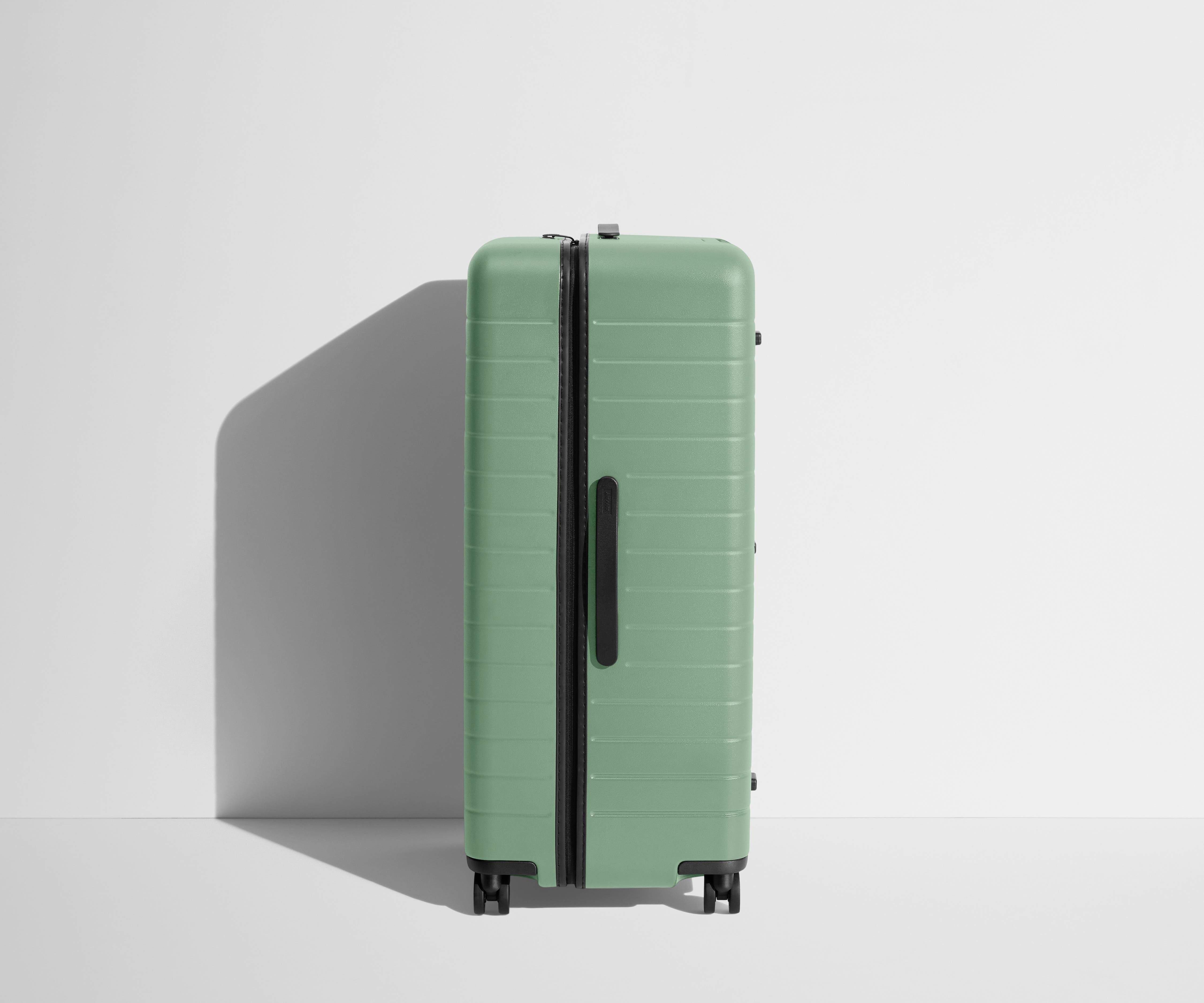 Side product view of The Trunk suitcase in Sea Green to show the slimmer top lid and deeper main compartment for easy access and packing