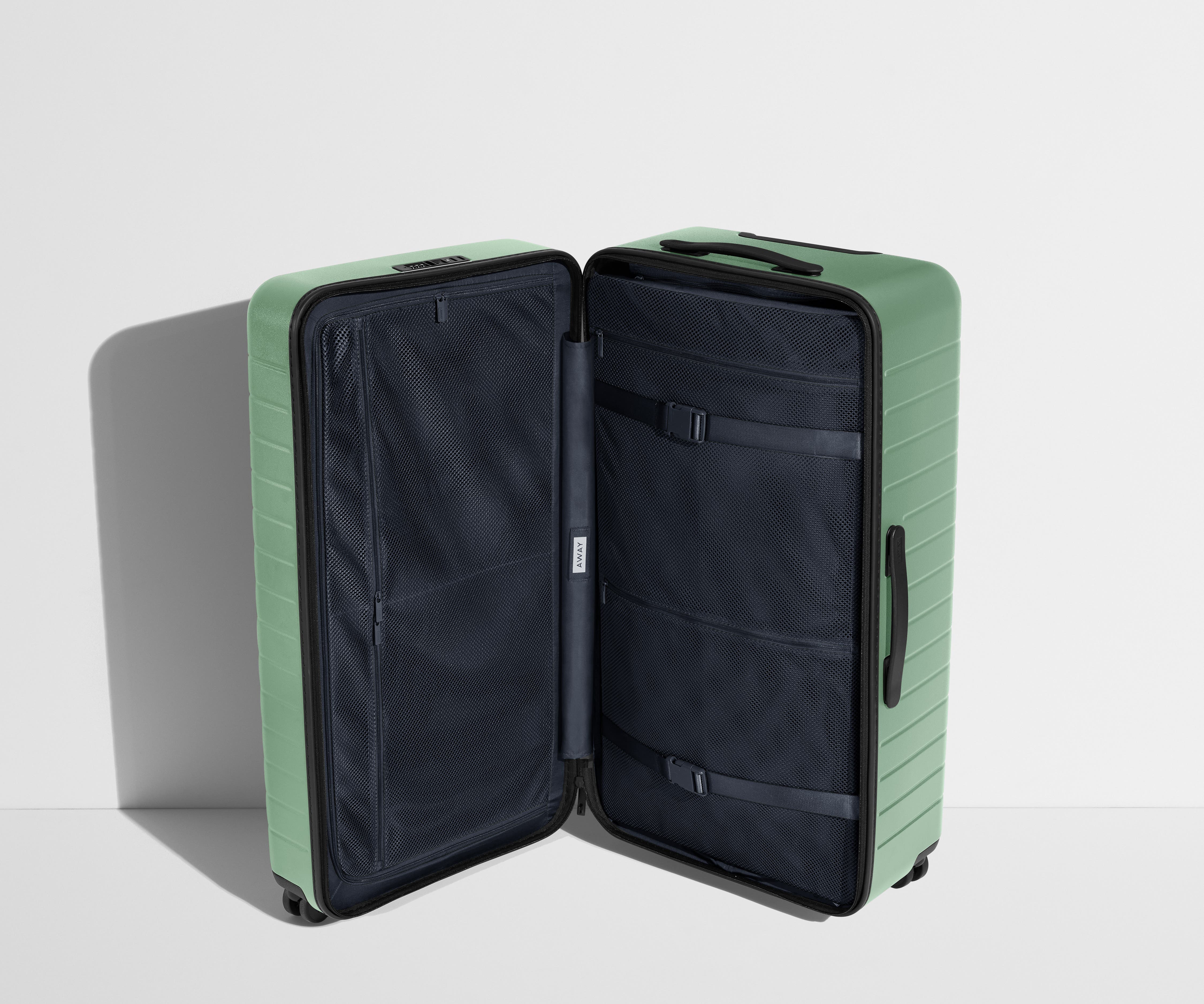 The Trunk suitcase in Sea Green shown open in an upright position to show interior organization and compression system