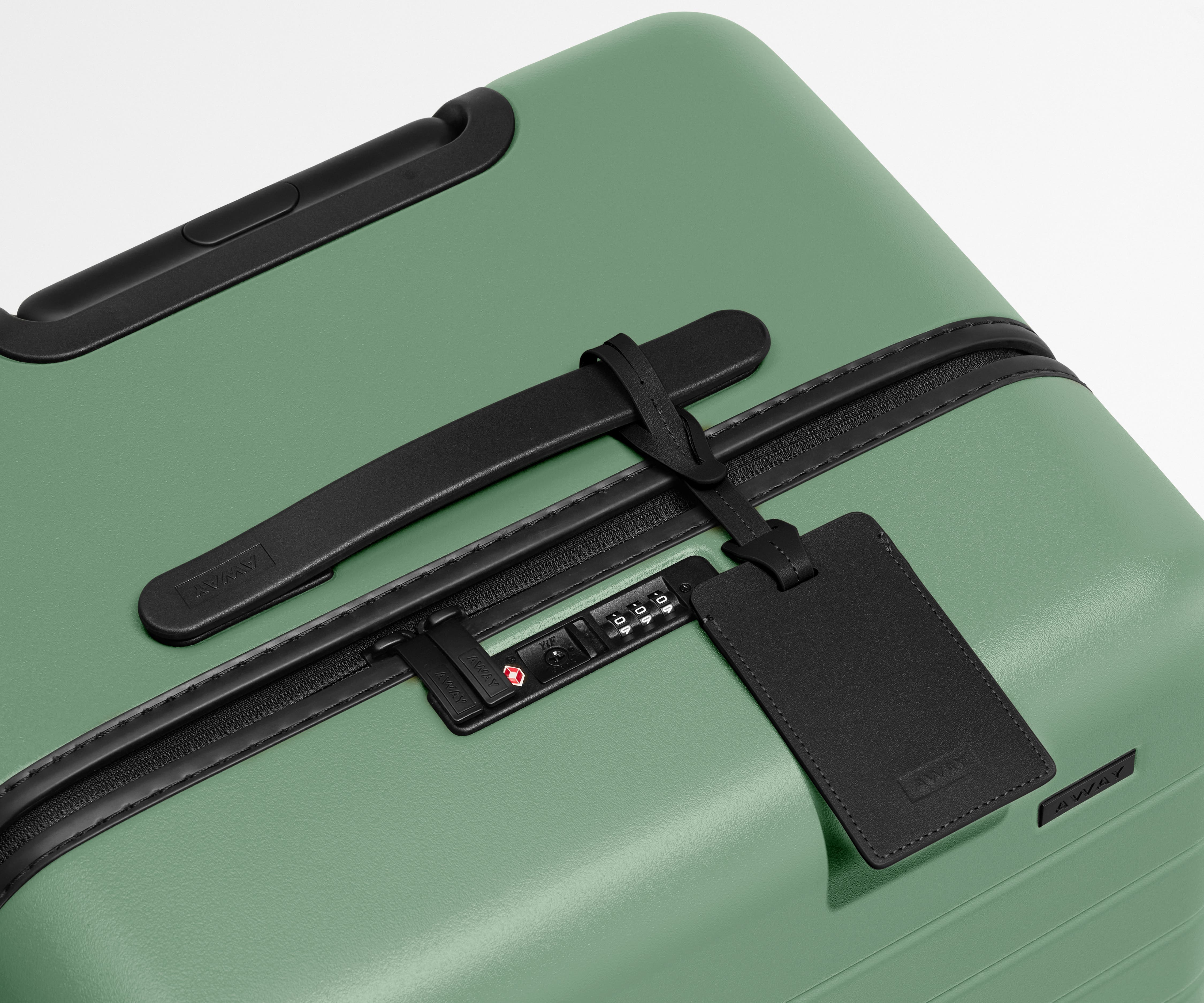 The Trunk suitcase in Sea Green shown shown from above highlighting TSA-approved combination lock and recycled leather luggage tag