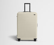 White suitcase with black handle on a light gray background